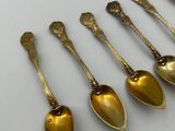 six spoons are lined up on a table with a box in the background