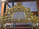 a mirror with a gold frame in the middle of a room