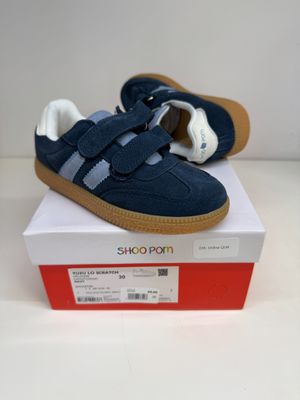 des chaussures bleues et blanches posées sur une boîte, sur une surface blanche