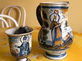 a pitcher and cup sitting on a table with a yellow tablecloth
