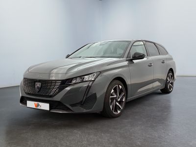 Une voiture grise est garée dans une grande pièce au sol noir.
