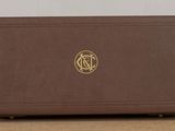 a brown suitcase sitting on a table with a gold logo on it