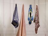 several different colored ties hanging on a clothes line in a room