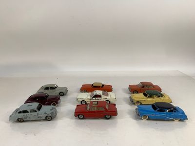 Six petites voitures sont alignées en rang sur une surface blanche.