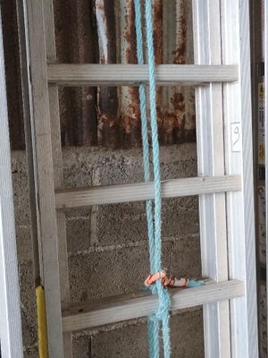 une corde bleue suspendue sur le côté d'une échelle