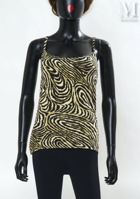 Le mannequin porte un haut noir et doré et un legging noir.