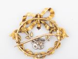 a close up of a gold brooch with a bird and a flower