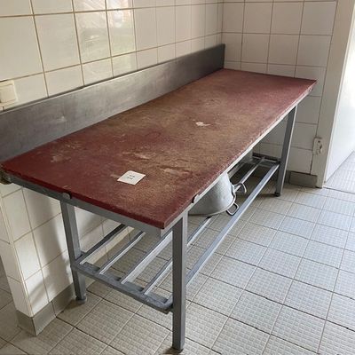 un plan de travail rouge dans une cuisine dont le mur est recouvert de carrelage blanc