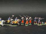 several figurines of men in uniforms riding horses and holding spears