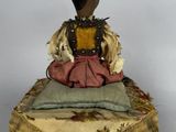 a small doll sitting on top of a cushion