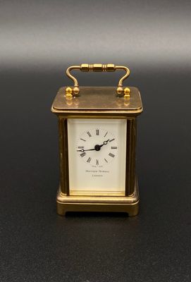 l'image d'une petite horloge dorée posée sur une surface noire
