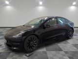 une Tesla Model 3 noire garée sur un sol à damier