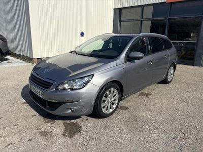 La voiture grise est garée devant un immeuble, sur un parking.