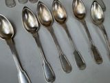 several spoons are lined up on a table with silverware