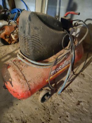 a small air compressor sitting on the ground in a garage