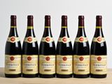 six bouteilles de vin sont alignées sur une table en bois