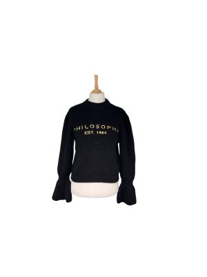 un pull noir avec des lettres dorées sur la poitrine et les manches