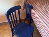 a blue chair sitting next to a table with a striped tablecloth on it