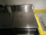 un plan de travail en inox avec une poubelle jaune en arrière-plan