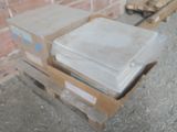 une pile de cartons posée sur une palette devant un mur de briques