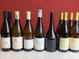 Six bouteilles de vin sont alignées sur une table devant un mur rouge.