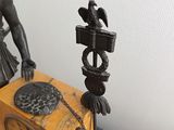a statue of a woman holding a clock on a table