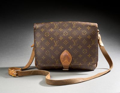 an old louis vuitton cross body bag on a gray surface