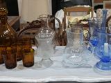 de nombreux vases et verres en verre de différentes couleurs sur la table