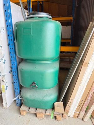 une pile de réservoirs verts posés sur une palette dans un entrepôt