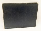 an old black book sitting on top of a table next to a white wall