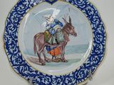 a blue and white plate with a picture of a man on a donkey