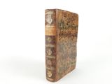 an old book sitting on top of a table on a white surface