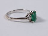 a close up of a ring with a green stone on it