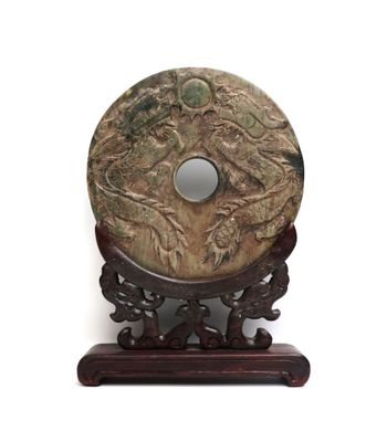 un disque de pierre sculpté posé sur un socle, sur fond blanc