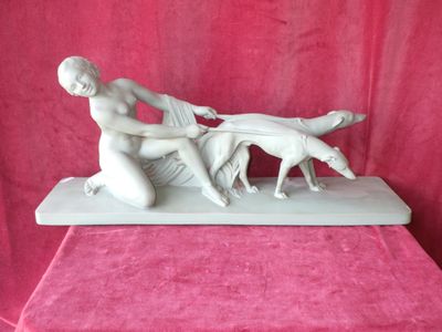 statue représentant une femme et un chien posée sur une table recouverte d'une nappe rose