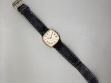 gros plan d'une montre sur une surface blanche avec un bracelet noir