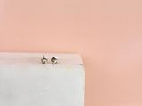 deux boucles d'oreilles en diamant posées sur un bloc de marbre blanc