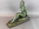 statue of a woman sitting on a rock on a white background