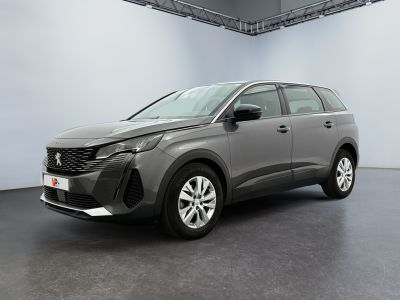 Une voiture grise est garée dans une grande pièce.
