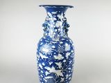 un vase bleu et blanc posé sur une surface blanche