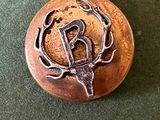 une image représentant un bouton en métal orné d'une tête de cerf