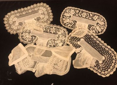 four pieces of white lace on a black surface