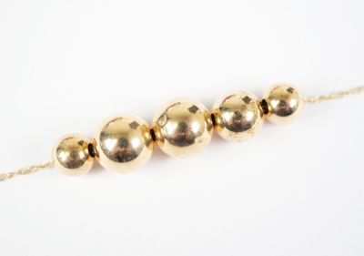 a close up of a gold bead necklace on a white background