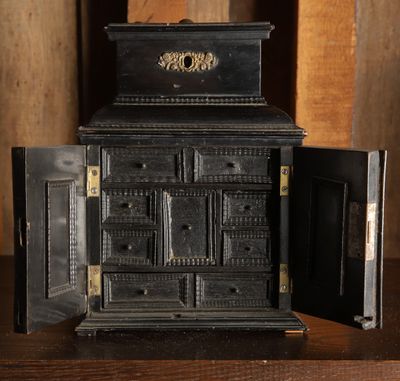 un vieux poêle noir dont la porte est ouverte, posé sur une table en bois