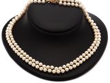 un ensemble composé d'un collier et d'un bracelet en perles blanches, présenté sur un mannequin noir
