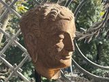 statue of a man ' s head sitting on a table in front of a fence
