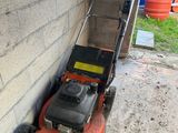 a lawn mower that is sitting on the side of the building