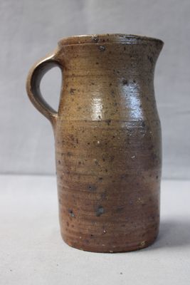 a brown vase with a handle on a table