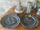 two pewwares on a wooden table with a vase in the background