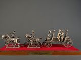 a silver figurine of a group of people riding in a horse drawn carriage